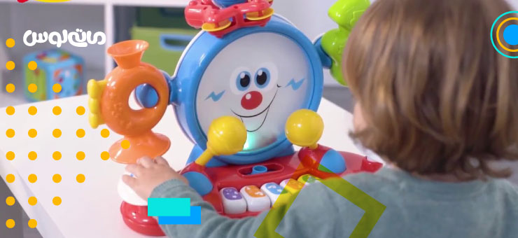 کودک خردسال در حال بازی با اسباب بازی موزیکال رنگی