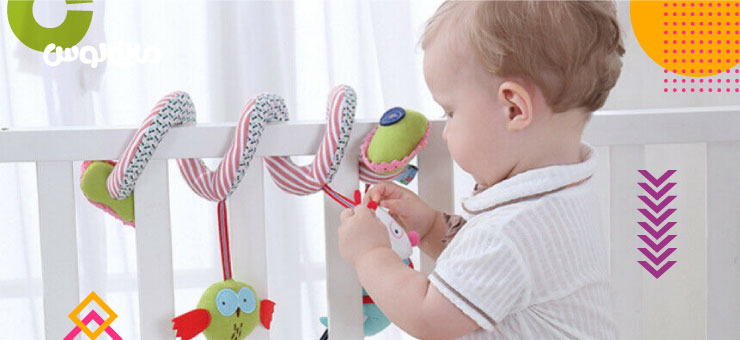 کودک در حال بازی با اویز کنار تخت