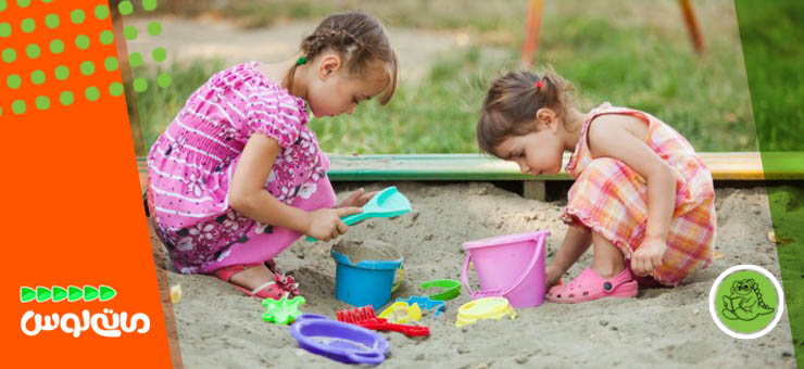 دو دختربچه درحال بازی با سطل شن و ماسه